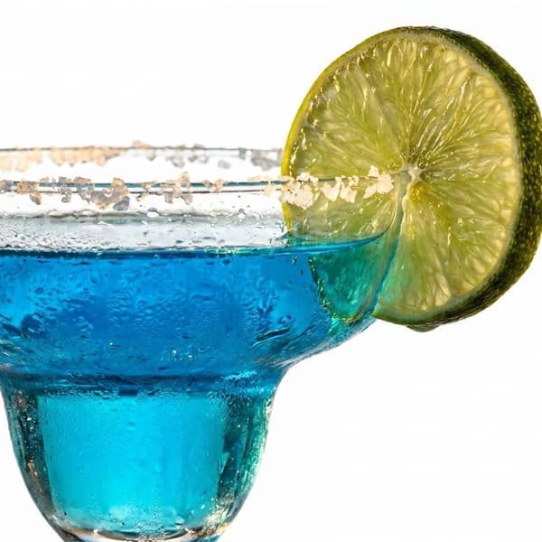 Close-up of a blue margarita with a salted rim and a lime slice on a white background.