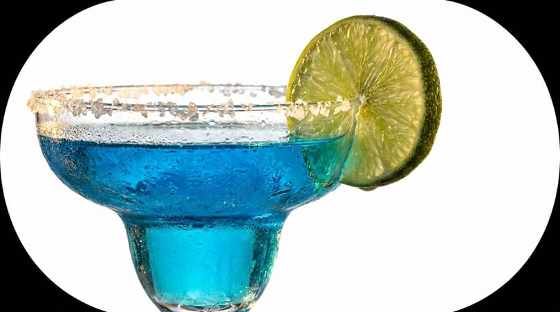 Close-up of a blue margarita with a salted rim and a lime slice on a white background.